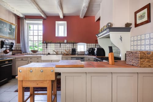 Spacious cottage kitchen at Les Lumieres Du Causse with red walls, beamed ceiling, and dining area overlooking the Causse