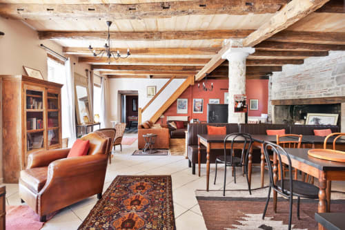 Spacious rustic cottage living area with exposed beams, leather seating, dining tables, fireplace and mountain views at Les