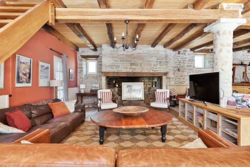 Spacious living room at La Vieille Dame cottage with exposed beams, fireplace, leather seating, and mountain views in