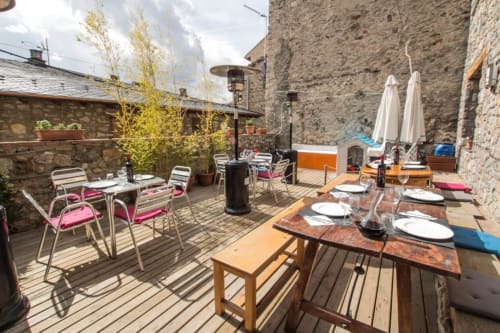 Terraza al aire libre del albergue La Calma De Bellver con mesas de comedor, sillas, sombrillas y muros de piedra en Bellver de la