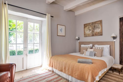 Bright bedroom at Les Lumieres Du Causse cottage with French doors, beige walls, wooden bed frame, and mountain views in