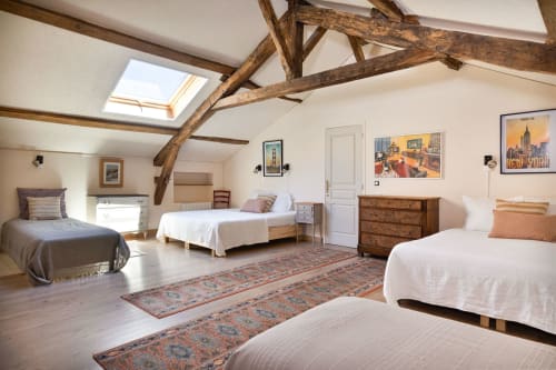 Spacious attic bedroom at Les Lumieres Du Causse cottage with exposed beams, multiple beds, wooden furniture, and skylight