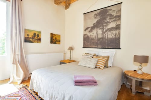 Bright bedroom in Les Lumieres Du Causse cottage with white bedding, wooden furnishings, and framed landscape art above