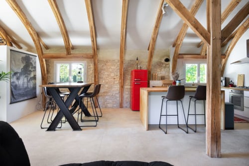 Loft moderne avec poutres en bois apparent, cuisine avec réfrigérateur rouge, table à manger, bar et murs en pierre aux Lumieres Du