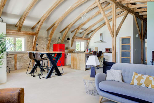 Spacieux loft La Grange Haute aux Lumières Du Causse avec poutres apparentes, canapé bleu, coin repas et rouge