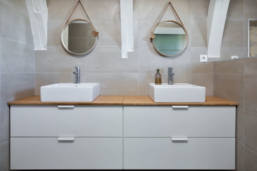 Vasque double de salle de bain avec plan de travail en bois, miroirs ronds et meubles blancs aux Lumières du Causse