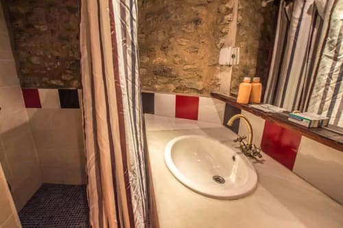 Baño moderno en el hostal La Calma De Bellver en Bellver de la Cerdanya con lavamanos redondo, ducha y azulejos decorativos rojos
