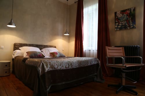 Modern bedroom at Le Grand Duc B&B in Valenciennes with dark bed, pendant lights, burgundy curtains, and garden view