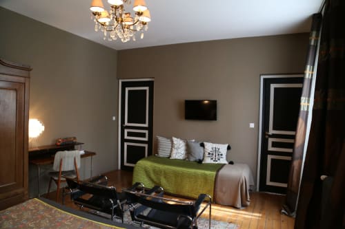 Chambre moderne au Le Grand Duc BnB à Valenciennes avec lit vert, portes noires, bureau, TV et lustre élégant