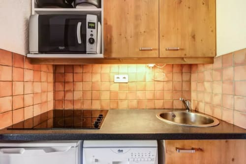 Coin de cuisine avec cuisinière en céramique, micro-ondes et évier de l'appartement CMD Méribel Le Pralin aux Allues, France