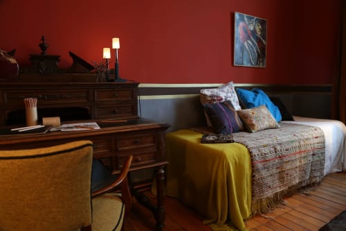 Cozy bedroom at Le Grand Duc, Valenciennes B&B with red walls, wooden desk, patterned bedspread and warm lighting