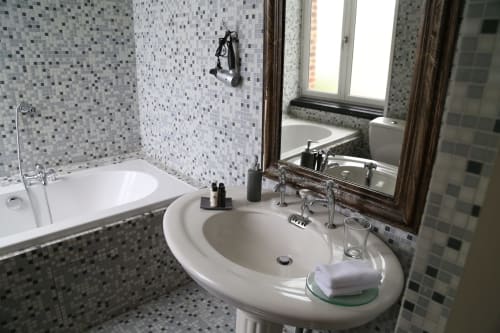 Modern bathroom with round white pedestal sink, mosaic tile walls, and bathtub at Le Grand Duc B&B in Valenciennes