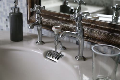 Luxury bathroom sink with chrome faucets and vintage wood-framed mirror at Le Grand Duc boutique hotel in Valenciennes