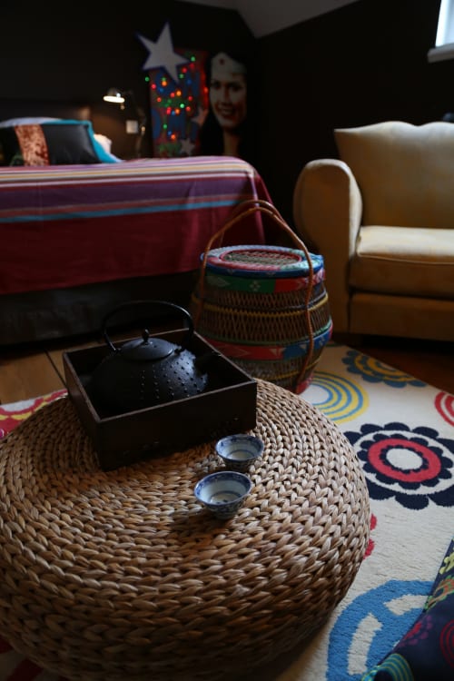 Cozy bedroom setup at Le Grand Duc in Valenciennes with woven table, black teapot, tea cups, and festive decorations