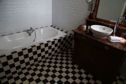 Salle de bain élégante du Le Grand Duc B&B à Valenciennes avec carrelage damier noir et blanc, baignoire blanche et meuble vasque en bois