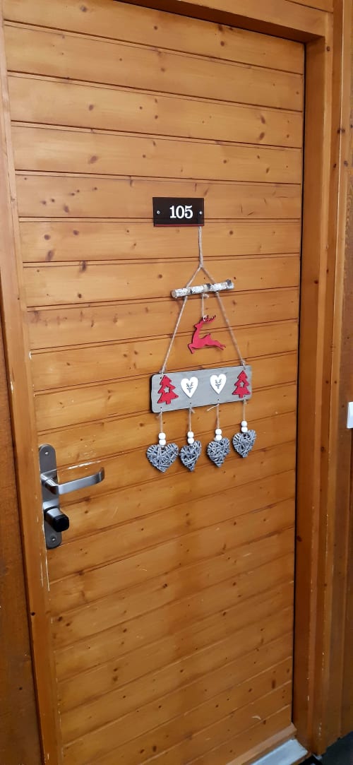Entrée de la chambre 105 au CMD Méribel Le Pralin avec porte en bois, plaque numérotée et décoration mobile festive