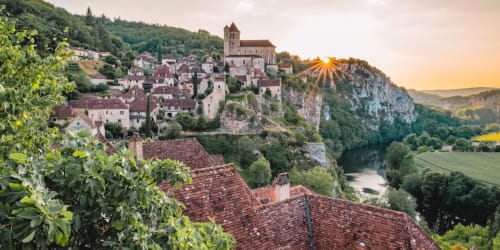 Village médiéval perché sur la colline avec son clocher, surplombant la vallée fluviale au coucher de soleil, Les Lumières Du Causse