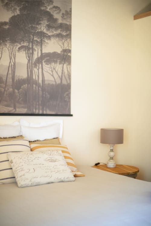 Cozy bedroom at Les Lumieres Du Causse B&B with forest artwork, striped bedding, and wooden nightstand