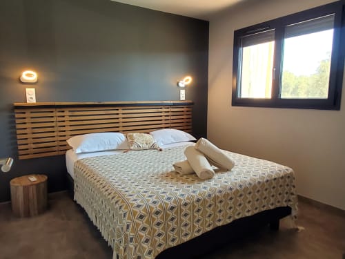 Modernes Schlafzimmer in den Villas Lantana in Lecci mit Holzkopfteil, gemusterter Bettwäsche und natürlichem Licht