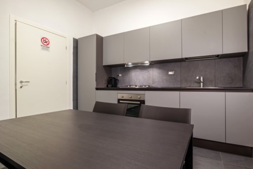 Cucina moderna dell'appartamento Casa Mirko ad Arezzo con mobili grigi, piano di lavoro scuro e tavolo da pranzo