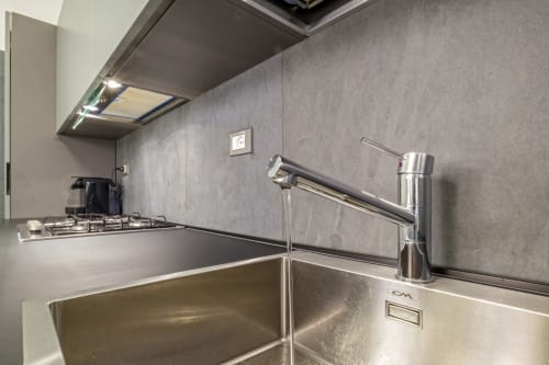 Cucina moderna con lavello in acciaio inossidabile, rubinetto cromato, piano cottura a gas e rivestimento piastrelle grigie a Casa Mirko