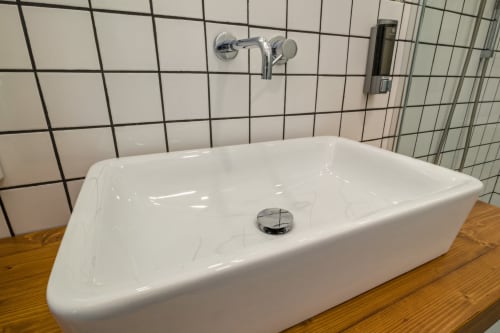 Moderno lavabo rettangolare bianco con rubinetto cromato e rivestimento in piastrelle nere nel bagno dell'appartamento Casa Mirko, Arezzo