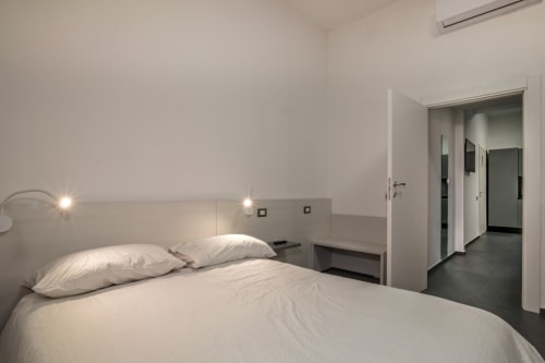 Camera da letto moderna a Casa Mirko ad Arezzo con letto bianco, testata minimalista e accesso al bagno ensuite