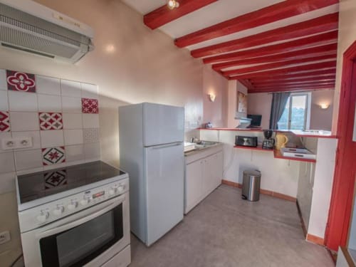 Cuisine moderne avec poutre rouge au plafond, électroménagers blancs et accents rouges au Refuge des Alpes mancelles, Fresnay-sur-Sarthe