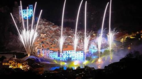 Spettacolo di luci notturne nel villaggio di Dolceacqua con fasci colorati che illuminano gli edifici e l'architettura storica