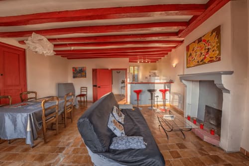 Le refuge des Alpes mancelles spacieux salon avec poutres rouges, cheminée, coin repas et mobilier moderne