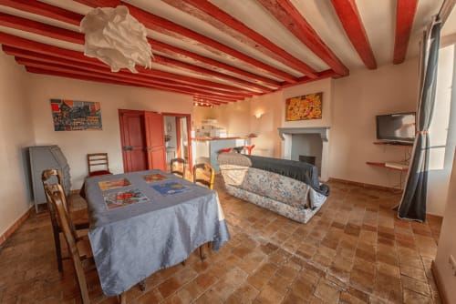 Chambre d'hôtes spacieuse au Refuge des Alpes mancelles à Fresnay-sur-Sarthe avec plafond rayé rouge, foyer et coin repas