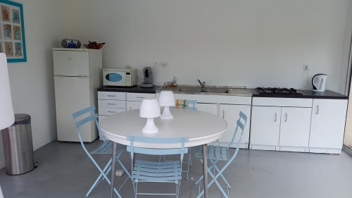 Cuisine moderne et espace repas du gîte Chez Anne Marie à Beausemblant avec table ronde et chaises bleues