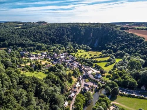 Aerial view of Fresnay-sur-Sarthe nestled in lush valley with river, forests, and green fields
