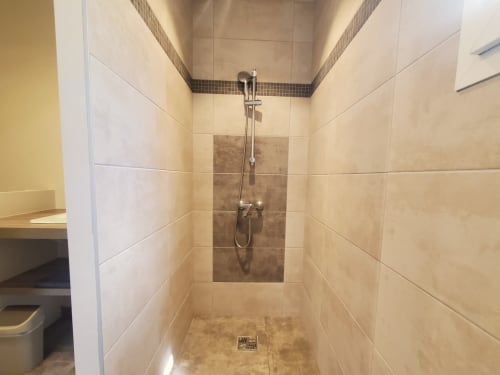 Modern walk-in shower with beige tiles and rainfall showerhead at Villas Lantana villa in Lecci