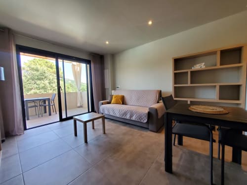 Modern 1-bedroom apartment living area at Villas Lantana, Lecci with furnished seating, dining table, and terrace access