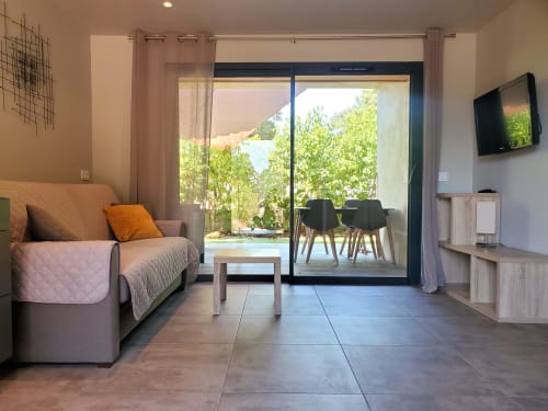 Modernes Wohnzimmer der Villas Lantana Lecci mit Sofa, Fernseher und Glasschiebetüren zur grünen Terrasse