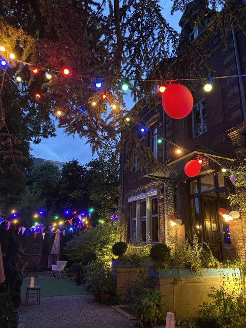 Cour du Grand Duc décorée de guirlandes lumineuses colorées et de ballons rouges au crépuscule, Valenciennes
