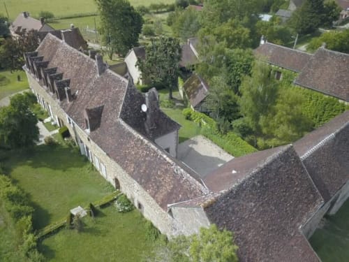 Vue aérienne du Prieuré Du Preux, un manoir en pierre historique aux toits de terre cuite à Sépeaux Saint Romain, France