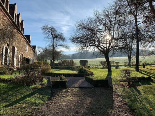 Le Prieuré Du Preux, manoir en brique dans la campagne française, jardins entretenus, arbres nus d'hiver et vallée pastorale