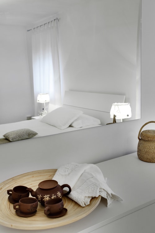 Minimalist Venice apartment bedroom with tea set, white bedding, and natural light from window