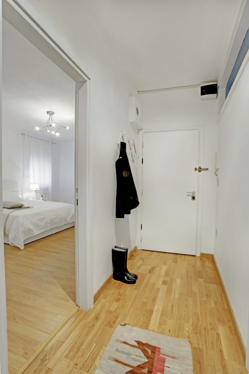 Bright entryway of La casa di Gemma apartment in Venice with wooden floors, white doors, and coat rack