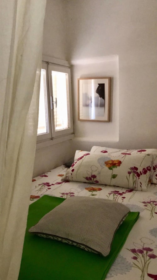 Cozy bedroom at Ca Cortigiane in Venice with floral bedding, green accent pillows, window with sheer curtains, and