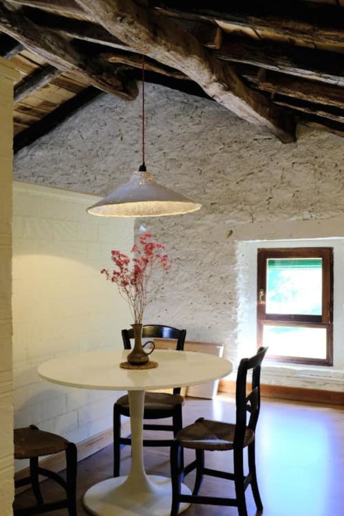 Comedor rústico en Casa rural MAÑARINEGI con mesa redonda, sillas negras, lámpara colgante y vigas de madera vista