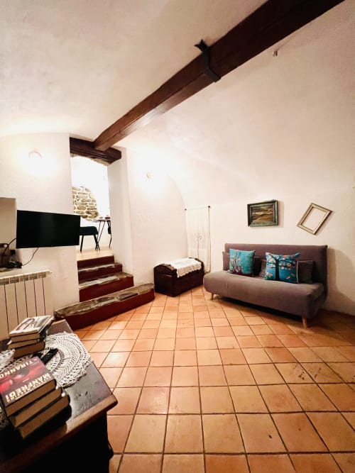 Spacieux séjour de l'Appartement Casté à l'Agritourisme Stecadò avec poutres en bois apparent, carrelage en terre cuite, canapé confortable