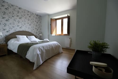 Moderno dormitorio en la cabaña Vivienda Balbino de León con papel de pared estampado de bambú, ventana de madera y vistas a la montaña