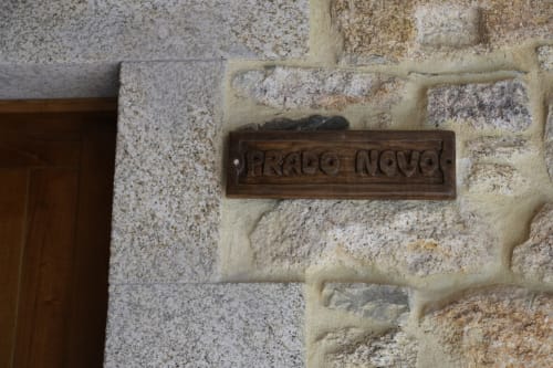 Letrero de madera 'Prado Novo' montado en la pared de piedra de la casa de Balbino en Suárbol, León, España