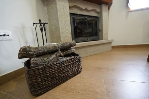 Chimenea con cesta tejida y leña en apartamento de montaña de Vivienda de uso turístico Balbino, León