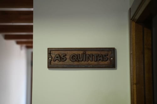 Cartel de madera 'As Quintas' en pared verde claro de Vivienda Balbino, apartamento rural en Léon, España