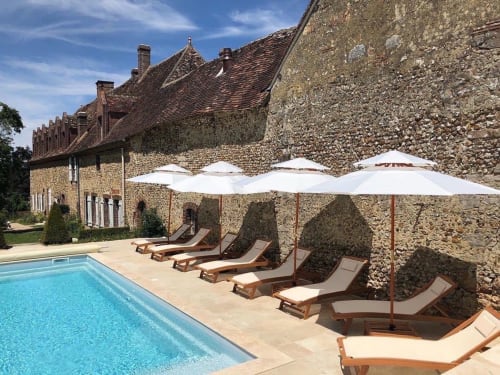 Piscine du Prieuré du Preux avec transats, parasols et manoir en pierre à Sépeaux Saint Romain