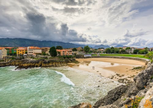 Vista de playa costera de Miyares con edificios coloridos y montañas, ubicación del hotel La Venta de Miyares en Asturias, España